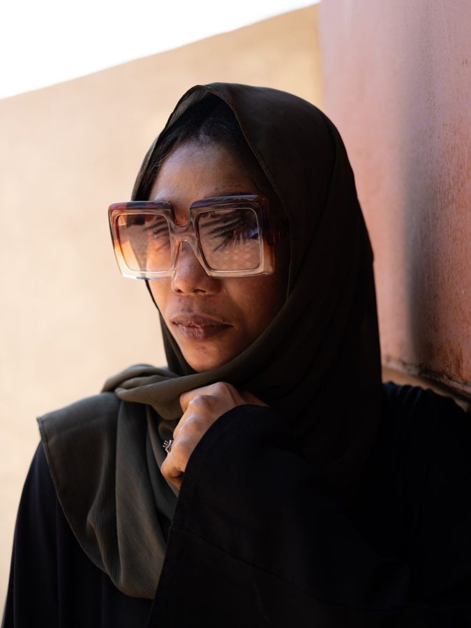 Aisha, Zanzibar, Tanzania: a woman in a black headscarf and tinted glasses, chin on her hand. Photograph by Marcus Vallance.
