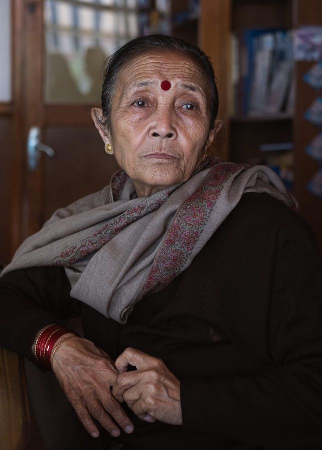 Anuradha Koirala, Nepal: an elderly woman in a grey shawl, hands folded. Photograph by Marcus Vallance.