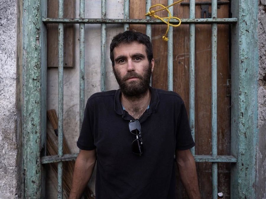 Harrison Stoker, Zanzibar, Tanzania: a bearded man in a black polo shirt in front of a weathered gate. Photograph by Marcus Vallance.