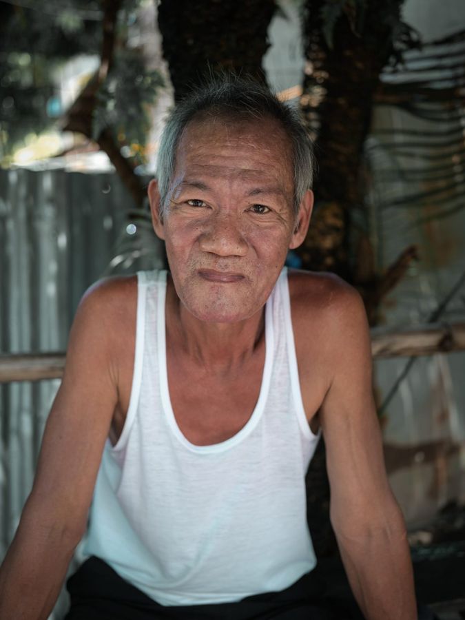 Portrait of a Man, Philippines: an older man in a white vest, seated. Photograph by Marcus Vallance.