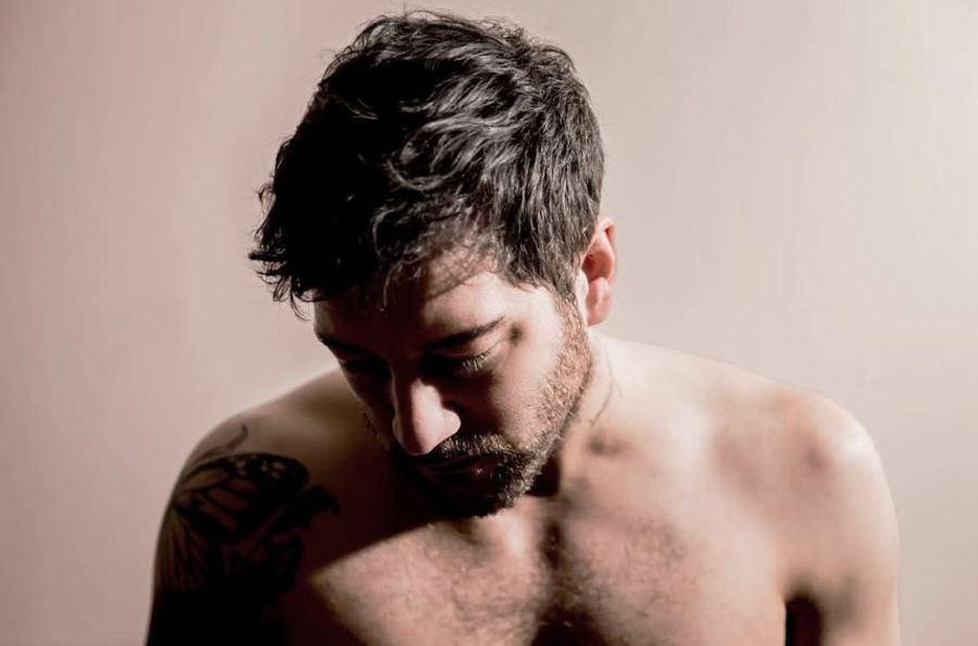 Matt Cardle, London, UK: a shirtless bearded man looking down, a tattoo on his shoulder. Photograph by Marcus Vallance.