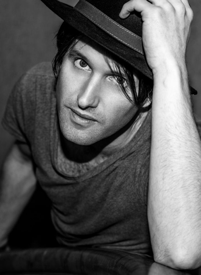 Tim Wheeler, Rome, Italy: black and white portrait of a man tipping his hat, leaning towards the camera. Photograph by Marcus Vallance.