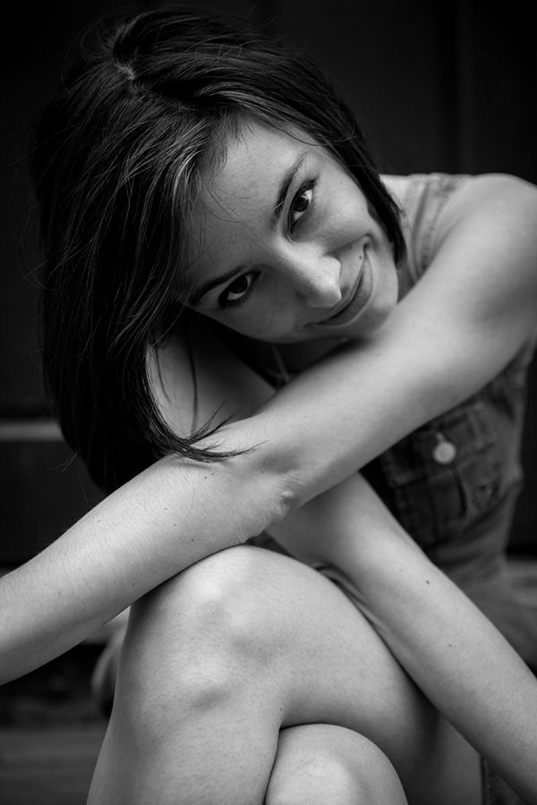 Margaux Billard, London, UK: black and white portrait of a woman resting her head on her arm, smiling. Photograph by Marcus Vallance.