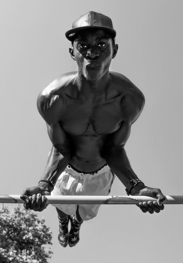 Athlete, Milan, Italy: black and white portrait of an athlete holding himself above a bar, seen from below. Photograph by Marcus Vallance.
