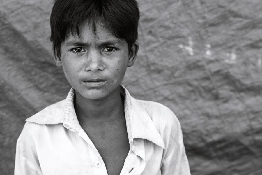 Portrait of a Boy, Kutupalong Refugee Camp, Bangladesh: black and white portrait of a boy in a white shirt looking intently into the camera. Photograph by Marcus Vallance.